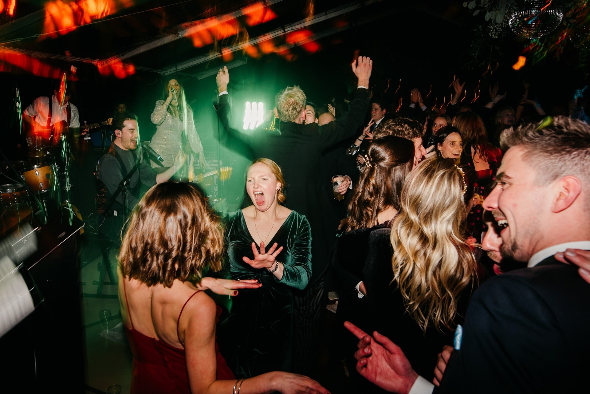 Guests dancing under green light, close to the band
