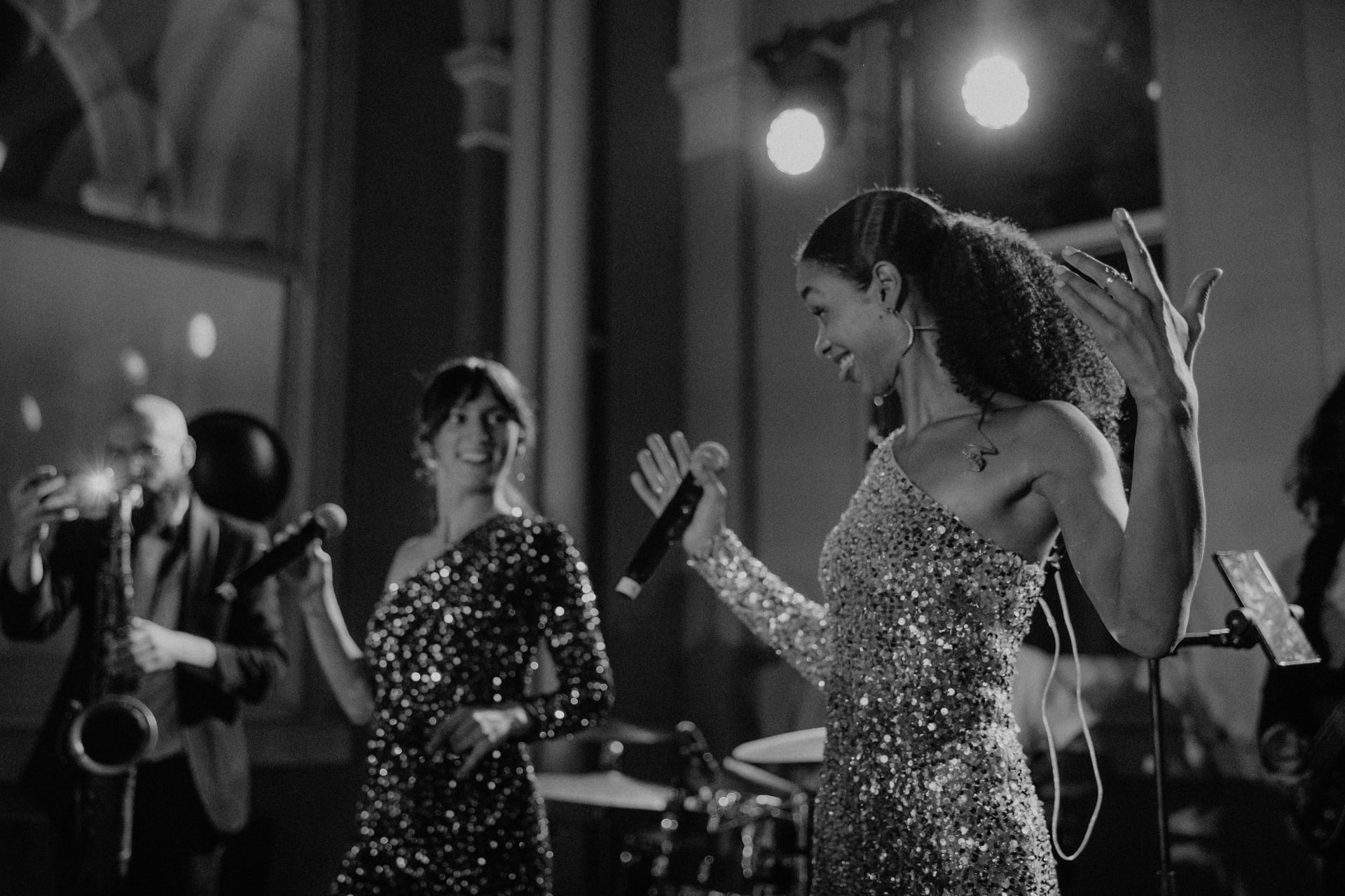 Two singers and a saxophonist on stage, in black and white
