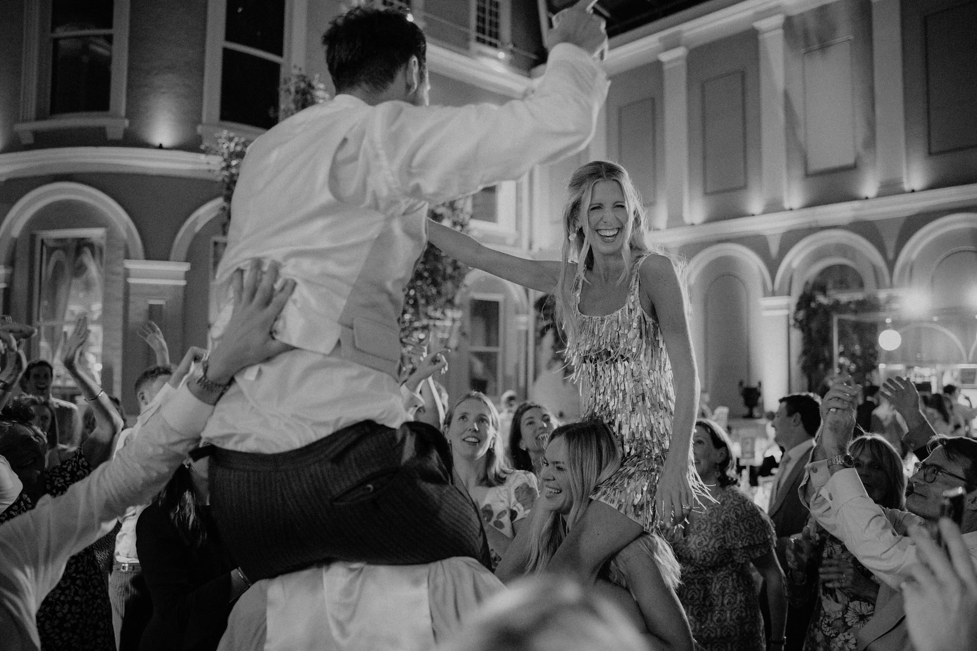 The couple on their friends’ shoulders, in black and white