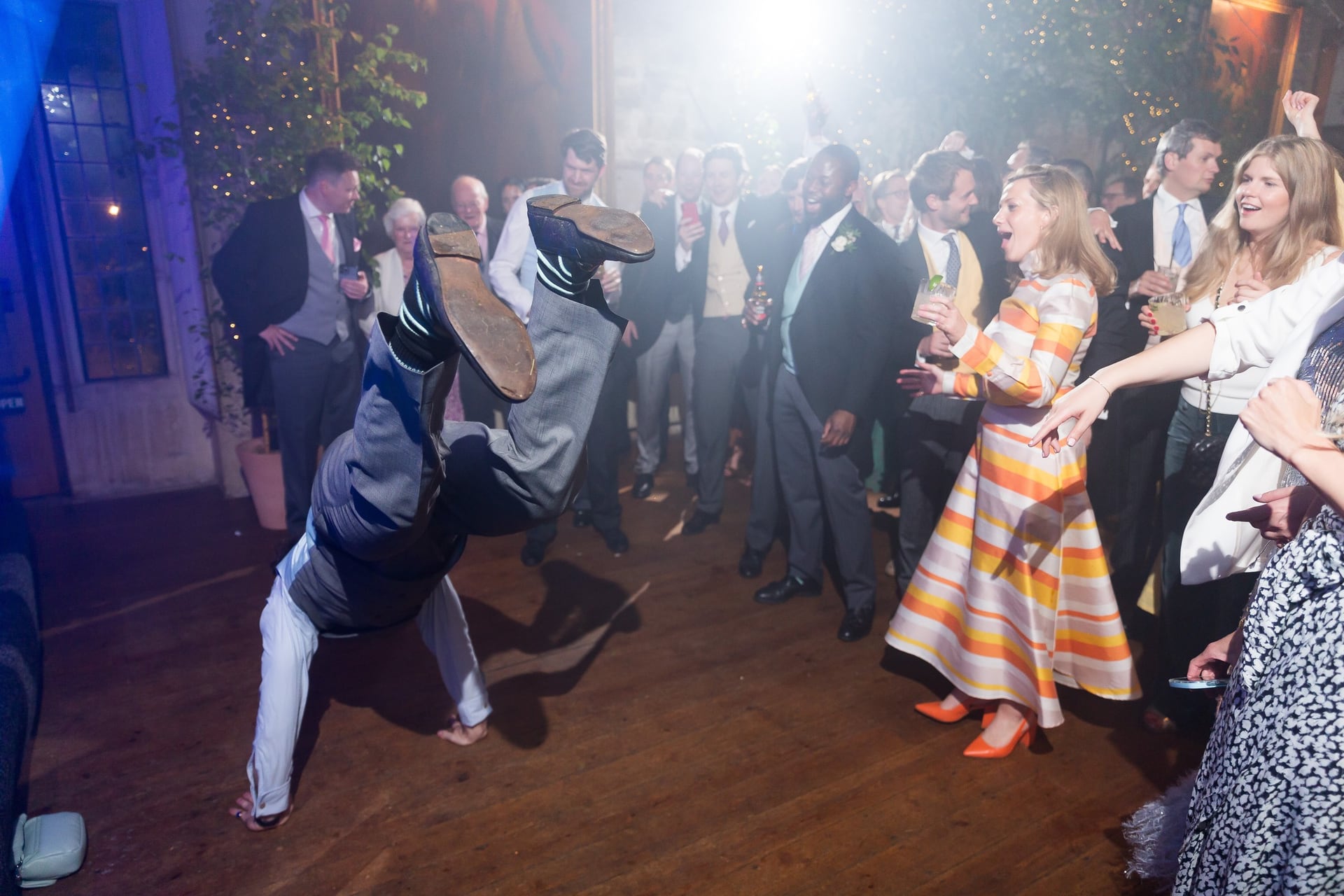 A guest mid-kick on a dance floor under blue light