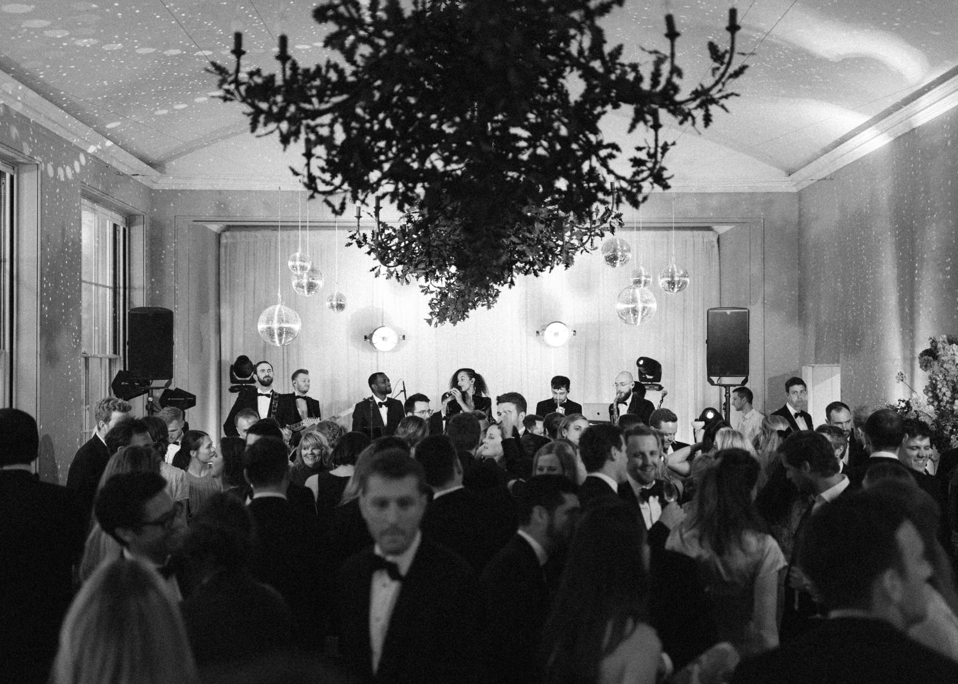 A ballroom under a hanging chandelier of greenery, in black and white